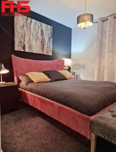 a bedroom with a large bed with a red headboard at Digbeth Luxury Apartment in Birmingham