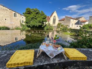 einen Tisch mit zwei gelben Stühlen und Flaschen Wein in der Unterkunft Les Bruyeres Chambres dhotes et Gite in Verteuil-sur-Charente