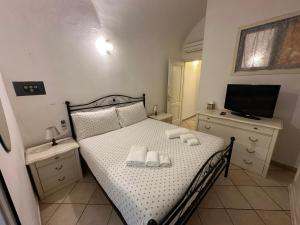 ein Schlafzimmer mit einem Bett mit Handtüchern und einem TV in der Unterkunft [2 passi dal mare di Alassio] Ampio trilocale in Alassio