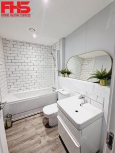 a bathroom with a sink and a toilet and a tub at Digbeth Luxury Apartment in Birmingham