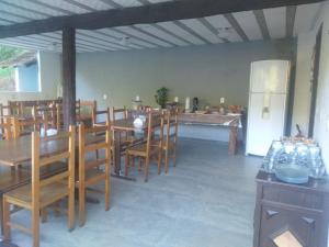 a dining room with a table and chairs and a refrigerator at Fazenda Piloes in Itaipava
