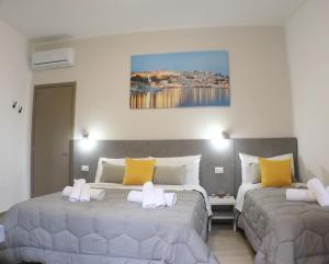 a bedroom with two beds with yellow and white pillows at Casa Lu Mari in Sciacca