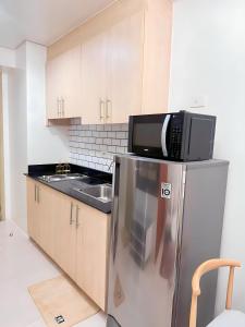 uma cozinha com um micro-ondas em cima de um frigorífico em Condo Unit near MOA, PICC, US Embassy and Airport em Manila