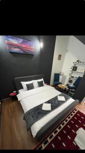 um quarto com uma cama grande e lençóis brancos em London.Apartments em Pristina