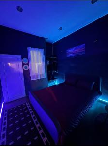 um quarto escuro com uma cama com luzes azuis em London.Apartments em Pristina