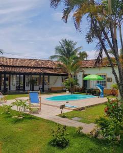 a house with a swimming pool and palm trees at Pousada Inn Engenho do Sonho in Rio das Ostras