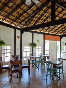 a dining room with tables and chairs and windows at Pousada Inn Engenho do Sonho in Rio das Ostras