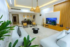 a living room with two white couches and a tv at Al Bandar Luxury Villa with 5BHK with private pool in Fujairah