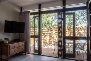 a living room with a television and a sliding glass door at Mill Park Garden Cottage in Gqeberha