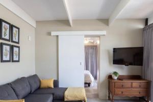 Una sala de estar con un sofá y un televisor de pantalla plana. en Mill Park Garden Cottage, en Gqeberha 2 fotos más