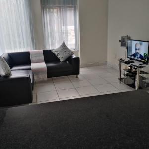 a living room with a couch and a tv at Posh 2 in Durban