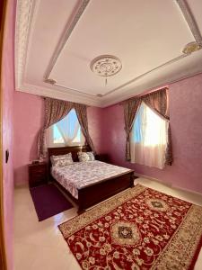 a bedroom with pink walls and a bed and a rug at La casa wadie 3 in Sidi Ifni