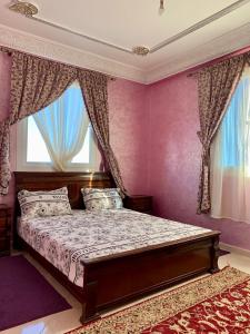 a bedroom with a bed with pink walls and a window at La casa wadie 3 in Sidi Ifni