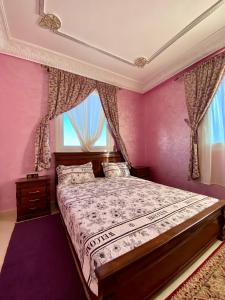 a bedroom with a bed with pink walls and a window at La casa wadie 3 in Sidi Ifni