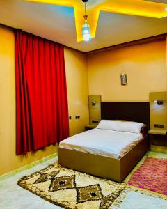 Schlafzimmer mit einem Bett mit roten Vorhängen und einem Teppich in der Unterkunft COMPLEXE L'OASIS in Erfoud