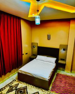 a bedroom with a bed and red curtains at COMPLEXE L'OASIS in Erfoud