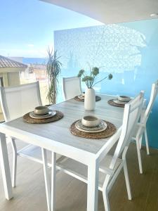 a white dining table with chairs and a white vase on it at Fantastic apartment in The Wave just steps from Carvajal Beach - Pool and free parking in Fuengirola