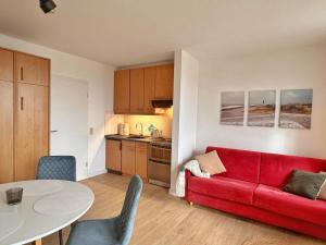 uma sala de estar com um sofá vermelho e uma mesa em Watt & Wind - Tolles Schwimmbad em Cuxhaven