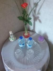 - une table en verre avec un vase et 2 bouteilles d'eau dans l'établissement La roseraie, à Aytré