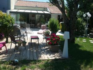 - une terrasse avec une table, des chaises et des fleurs dans l'établissement La roseraie, à Aytré