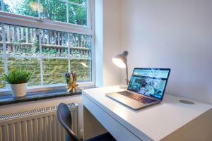 a laptop computer sitting on a desk next to a window at Avenue Apartment - Close to City Centre - Free Parking, Super-Fast Wifi and Smart TV by Yoko Property in Northampton