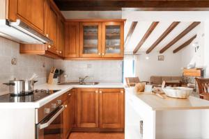 een keuken met houten kasten en witte aanrechtbladen bij Casa Nadalina in Višnjan