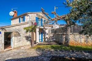 een stenen huis met blauwe deuren en een boom bij Casa Nadalina in Višnjan