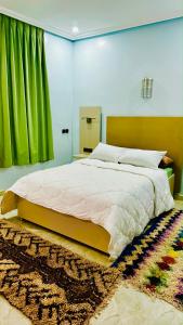 a bedroom with a large bed with a green curtain at COMPLEXE L'OASIS in Erfoud