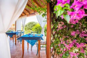 a dining room with blue tables and pink flowers at B&B La Vela Chia in Chia