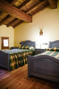 2 letti in una camera con pavimenti e soffitti in legno di Villa Contrà Facci - Strada 52 gallerie del Pasubio a Schio