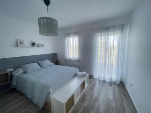 a white bedroom with a large bed and two windows at Apartamento El Castell in Alaquas