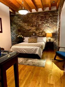 - une chambre avec un lit et un mur en pierre dans l'établissement HOTEL MINA REAL, à Real de Catorce
