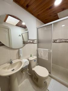 uma casa de banho com um lavatório, um WC e um espelho. em Monte Paz Finca Hotel em Montenegro