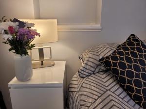 a bedroom with a bed and a vase of flowers on a night stand at 39 Queens Road in Swanage