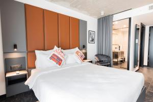 a bedroom with a large white bed with pillows at The Londoner Hotel St. Julian's in St. Julianʼs