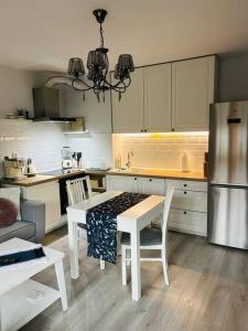 a kitchen with a table and a refrigerator at Komfortowy apartament Krokusowa 6 in Krakow