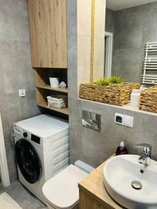 a bathroom with a washing machine and a sink at Komfortowy apartament Krokusowa 6 in Krakow