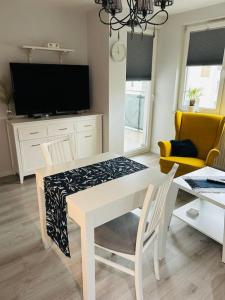 a living room with a white table and a tv at Komfortowy apartament Krokusowa 6 in Krakow