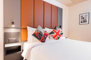 a bedroom with a white bed with an orange headboard at The Londoner Hotel St. Julian's in St. Julianʼs
