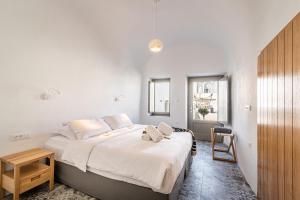 Un dormitorio con una gran cama blanca con una silla. en Veneston Suites, en Fira 65 fotos más