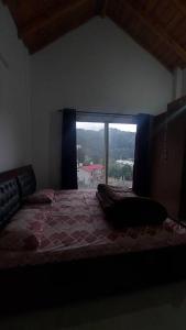 a bedroom with a bed with a large window at Entire 1 BHK Cottage in Nainital