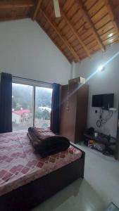 a bedroom with a bed and a large window at Entire 1 BHK Cottage in Nainital