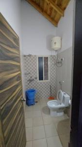 a bathroom with a toilet and a blue trash can at Entire 1 BHK Cottage in Nainital