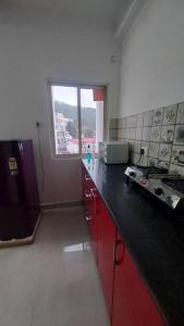 a kitchen with red cabinets and a window at Entire 1 BHK Cottage in Nainital