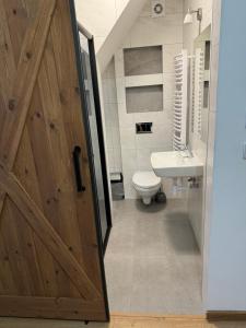 a bathroom with a wooden door and a toilet at Orawska Knieja 2.0 in Lipnica Wielka