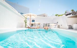 una mujer parada en una piscina en una casa en Veneston Suites, en Fira