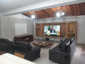 アチバイアにあるCondominio recreio da montanhaのリビングルーム(黒革の家具、テレビ付)