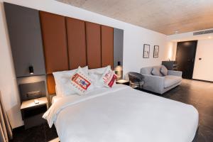 a bedroom with a large white bed and a chair at The Londoner Hotel St. Julian's in St. Julianʼs