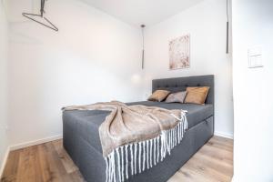 ein Schlafzimmer mit einem grauen Bett mit einer Decke in der Unterkunft *MODERN & MINIMALISTIC* Design-Apartment I Stadtmitte in Wesel