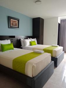 two beds in a room with green and white at Hotel Tupinamba Neiva in Neiva